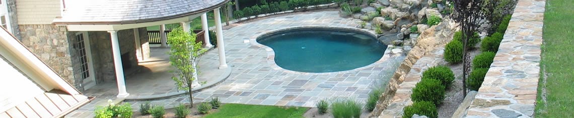Beautiful inground pool with stone landscaping and gorgeous retaining wall.